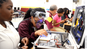 Training for high-tech: In Chattanooga, Tennessee, Tyner Academy students (from left) Jada Beckett and Takayla Sanford work on building circuits, while “mechatronics” teacher Bryan Robinson instructs Brookeana Willams and Noemy Marberry about soldering.