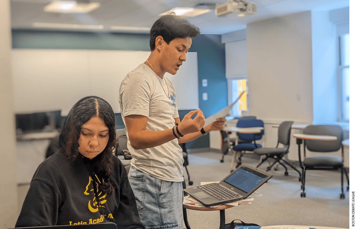 Boston Latin Academy student Rinji Sherpa delivers a speech while teammate Adriana Carvajal finds evidence to support his arguments during a live debate.