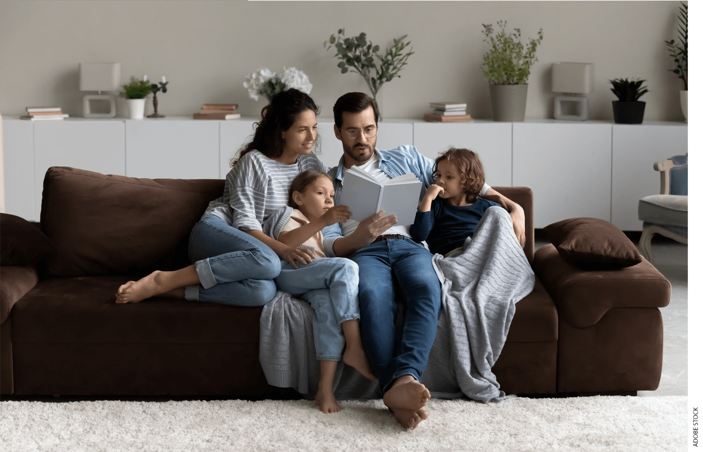 Family of four reading together on a couch