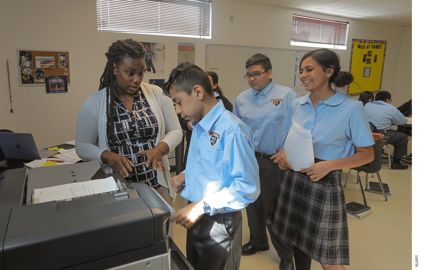 A teacher and three students using a copy machine