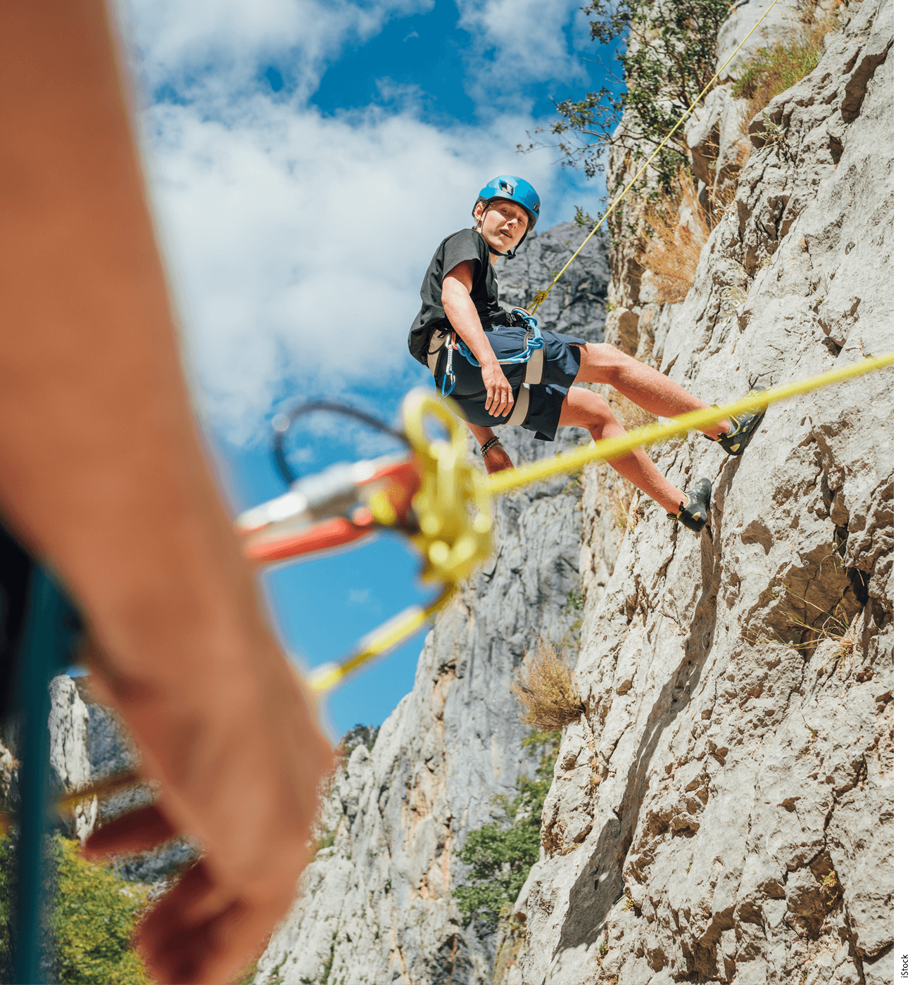 A climber is suspended by a cable on the side of a mountain