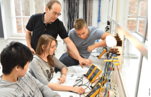 A teacher leads a technical lesson with three students