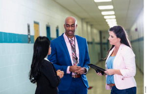 Teachers speak in the hallway of a school