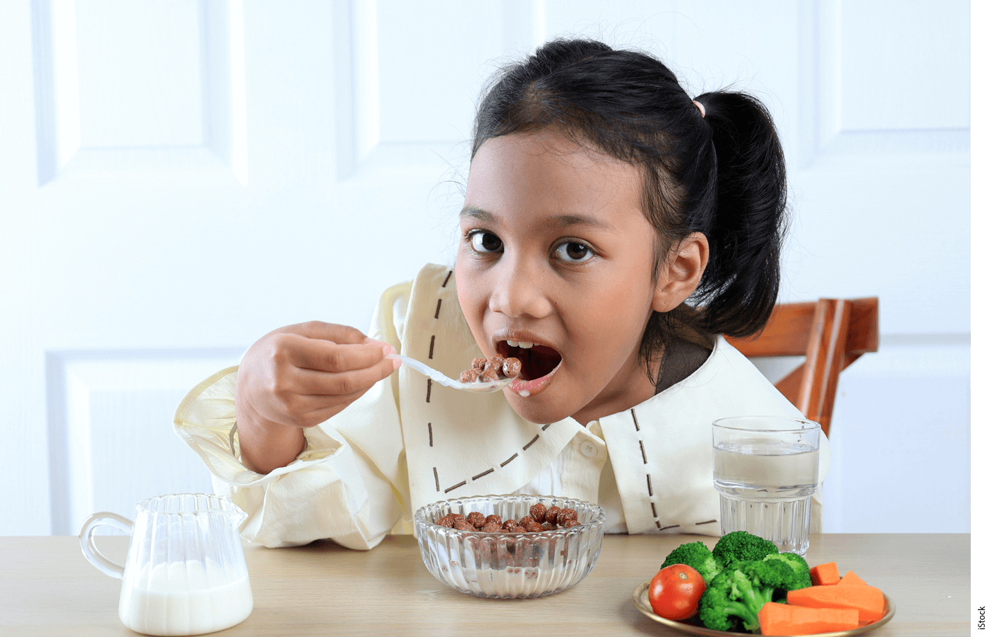 Photo of a girl eating vegetables at a table