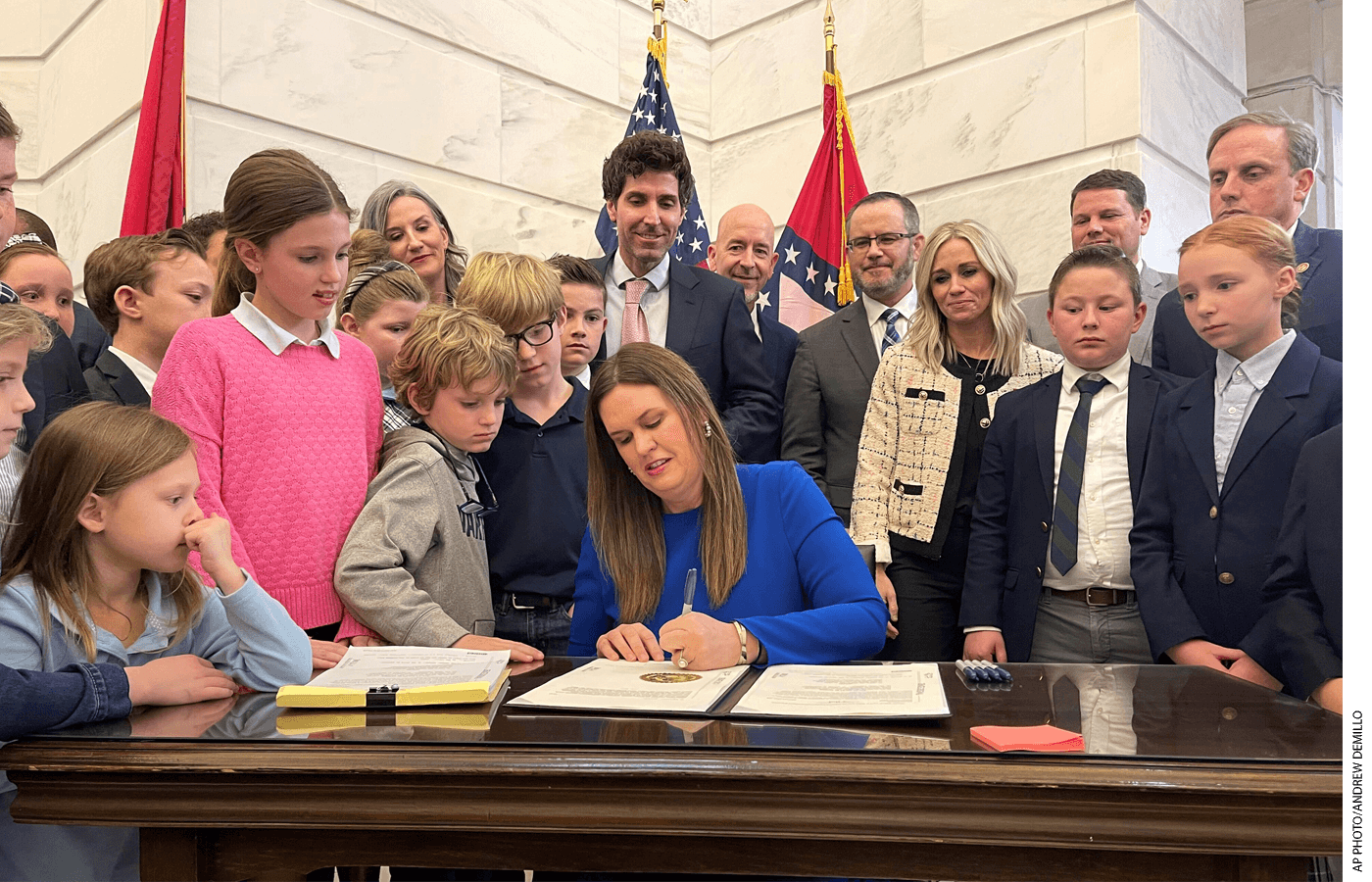 Arkansas Governor Sarah Huckabee Sanders signs a bill at a desk