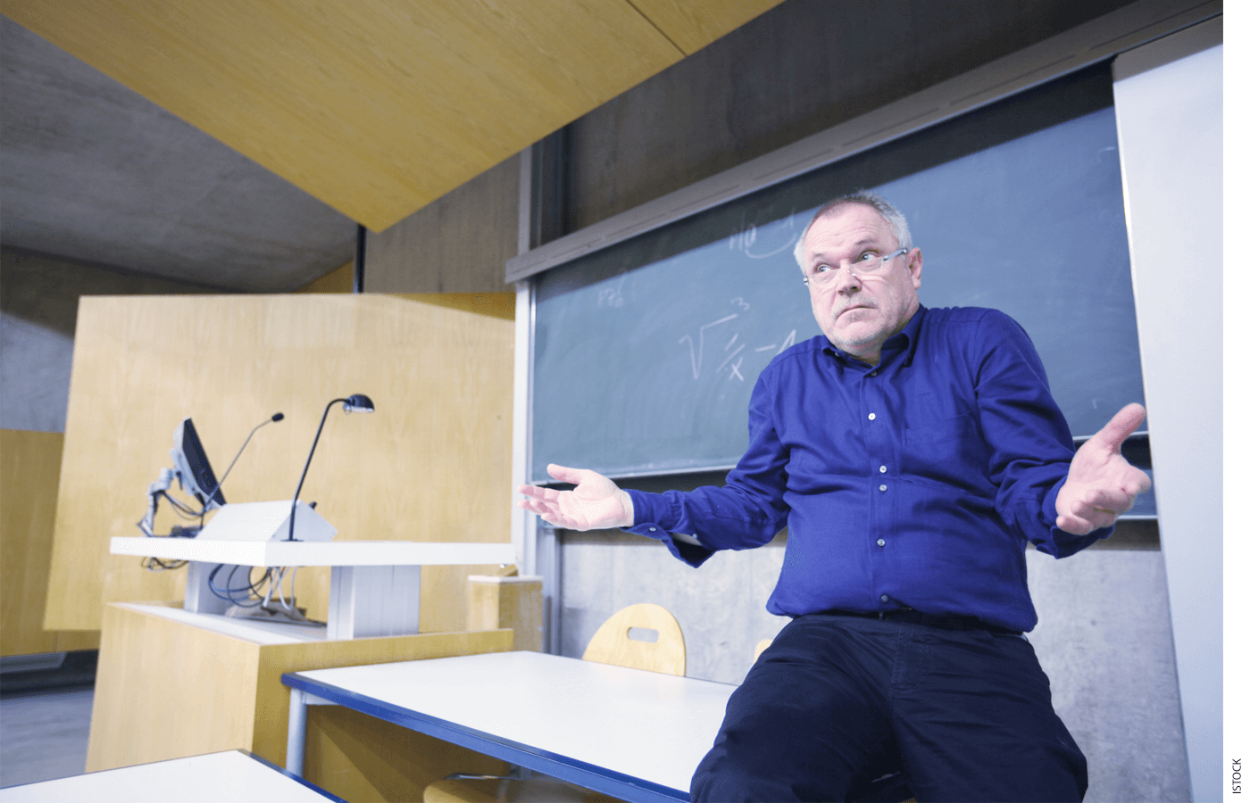 College professor at front of lecture hall shrugging shoulders