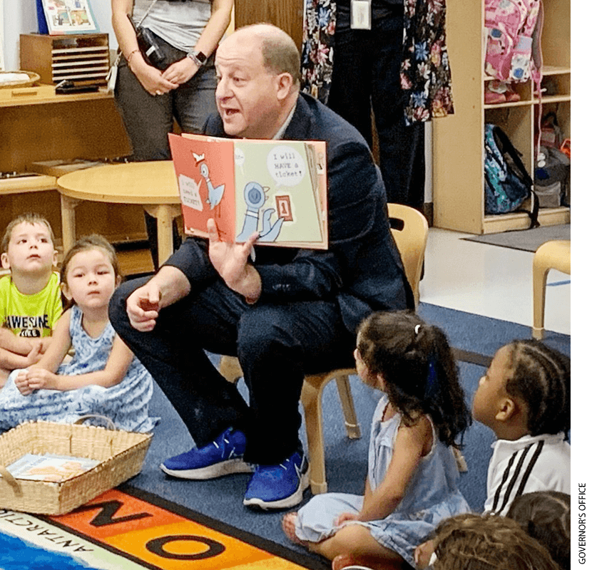 Photo of Colorado Governor Jared Polis reading to students in a classroom